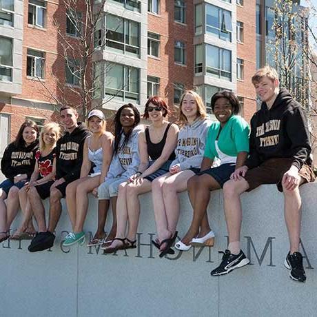 Smiling students sitting on Framingham State University wall on Accepted Students Day
